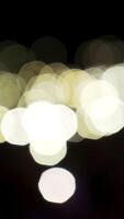 desfocado bege luzes comovente lentamente em Preto fundo. Ação. fluindo bokeh brilhante círculos do luz dentro a escuro, borrado fundo. video