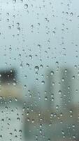 proche en haut de une verre fenêtre sur une pluvieux journée avec gros gouttes sur flou ville ang gris lourd ciel Contexte. Stock images. transparent l'eau gouttes sur une verticale verre surface. video