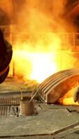 Rear view of two steelmakers at ingot casting shaking hands in front of electric arc furnace in hot shop, metallurgical production. Stock footage. Heavy industry and agreement concept. video