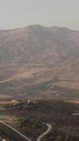 Breathtaking landscape with a large mountain covered with fog and green valley at its foothill. Action. Aerial of the cloudy mountain peak and the village. video