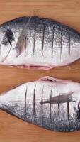 Top view of process of cooking fish. Action. Close up of raw fish being cut, salted and spicied, ant then grilled with mushrooms, tomatoes and slices of orange, healthy food concept. video