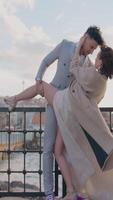 Newlyweds on background of pier. Action. Beautiful newlyweds pose between city buildings. Stylish newlyweds hug on background of city pier in cloudy weather video