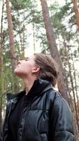 Beautiful woman hiking in the forest and stretching hands to the trees. Concept. Freedom and harmony, girl with curly hair enjoying solitude in pine tree forest. video