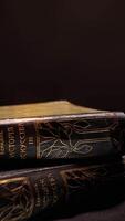 Vintage books with dark leather binding and patterns on isolated background. Stock footage. Old book with simple gilded patterns on cover video