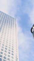 Bottom view of modern multi-storey buildings on background of blue sky. Action. Simple architecture of modern residential high rises with glass design reflecting blue sky video