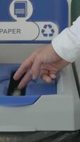 jogando uma peça do papel dentro uma especial bin para desperdício reciclando, conceito do ecologia. hdr. fechar acima do masculino mão colocando uma pequeno Folha do papel dentro uma reciclando bin. video