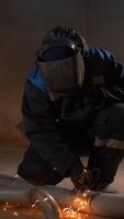 Worker welding metal pipe with many sparks are flying in different directions in the dark. Clip. Metalworking with hand-held power tools. video