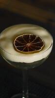 Close up of beautiful cocktail with thick foam and dried orange slice. Media. Beverage on bar counter background. video