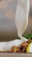 Close-up of some person's hand adding sour cream at the bowl with solyanka. Stock footage. Russian solyanka soup with meat, sausages and olives video