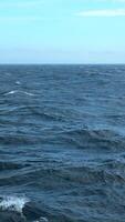 Beautiful view of horizon of blue sea with waves. Clip. Foam from waves of floating ship in blue sea. In blue sea with waves on background horizon with blue sky video