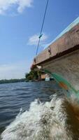 Fishing boat in the river, first person view. Action. Old boat floating along green shore and blue cloudy sky on the background. video