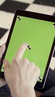 Close-up of man holding tablet and touching green screen. Stock fooatge. Young freelancer uses tablet to work or create projects. Tablet with green screen to insert video