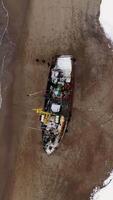 Top view of sail ship wrecked on the coast in Antarctica. Footage. Flying above the winter snowy coast by the sea and the old rusty ship. video