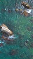 Top view of beautiful wild coast with rocks in water. Clip. Coastline with rocks and waves near shore. Inspiring nature of sea coast with variety of rocks video