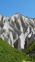 Amazing white mountains with green grass. Clip. Beautiful patterns on rocky white mountain with bright greenery on sunny summer day. White rocks of volcanic origin on island on summer day video