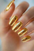 Elegant gold metallic nails displayed on a woman's hand showcasing intricate design and shine photo