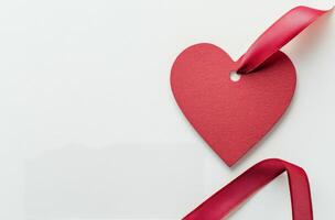 Red heart-shaped tag with a ribbon on a white background for Valentines Day or love occasions photo