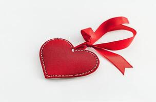 A close-up of a red leather heart tag with a satin ribbon on a white background photo