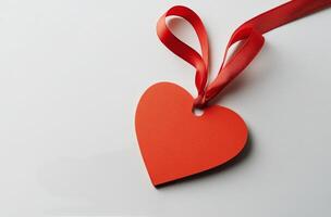 A close-up of a red leather heart tag with a satin ribbon on a white background photo