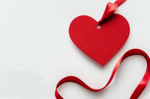 Red heart-shaped tag with a ribbon on a white background for Valentines Day or love occasions photo