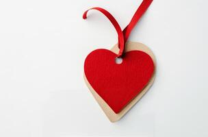 Red heart-shaped tag with a ribbon on a plain white background photo
