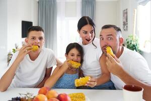 Family enjoying fresh corn on the cob in a bright kitchen during a sunny afternoon photo