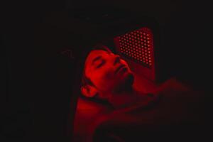 Facial skin care using an LED lamp in a beauty salon. photo