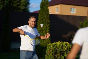 Man playing badminton outdoors in a backyard during sunny weather photo
