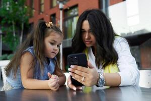 Mother and daughter enjoy time together while looking at a smartphone on a sunny day photo