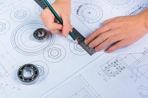 A person is holding a ruler and drawing on a blueprint photo
