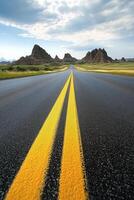 A long road stretches through golden grasslands towards distant rock formations at sunset photo