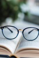 Glasses resting on an open book in a library setting during daytime photo