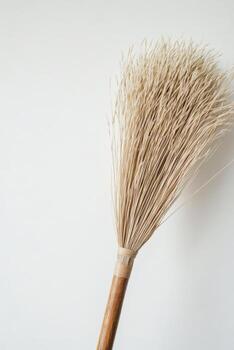 Natural straw broom displayed on a clean white background for decorative or practical use photo