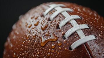A close-up of a wet football showcasing water droplets on its surface during a rainy game photo