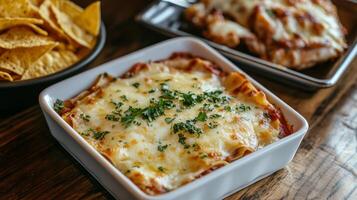 Delicious baked pasta with cheese and herbs served alongside nachos on a wooden table photo