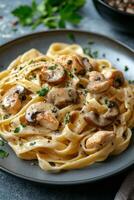 Creamy chicken fettuccine with mushrooms served on a rustic wooden table photo