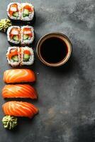 Fresh sushi arranged with salmon slices, cucumber rolls, and a bowl of soy sauce photo