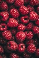 Fresh raspberries with green leaves on a wooden surface during daylight hours photo