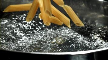 Penne pasta falls into boiling water. Filmed on a high-speed camera at 1000 fps. High quality FullHD footage video