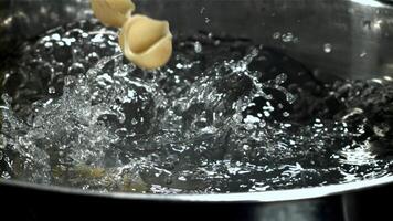 The pasta falls into the boiling water with splashes. Filmed on a high-speed camera at 1000 fps. High quality FullHD footage video