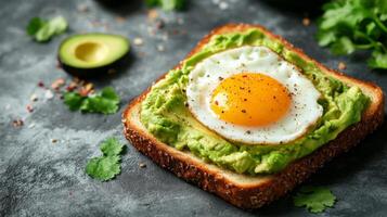 Avocado toast with fried egg on rustic bread topped with herbs photo