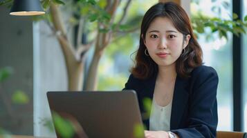 A woman in a business suit sitting at a table with a laptop photo