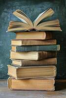 Stacked vintage books with an open book on top against a chalkboard background photo