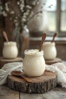 Fresh yogurt in a glass jar on a rustic wooden table beside a window photo