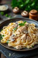 Creamy chicken fettuccine with mushrooms served on a rustic wooden table photo