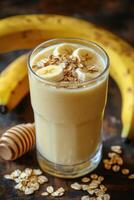 Creamy banana smoothie topped with oats and honey on a wooden table photo