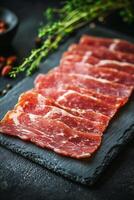 Assorted slices of cured meat arranged on a dark stone platter photo