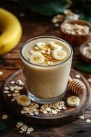 Creamy banana smoothie topped with oats and honey on a wooden table photo