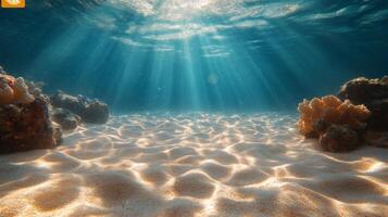 Sunlight filtering through clear turquoise water reveals a sandy ocean floor with coral formations photo