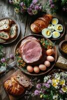 A rustic table arrangement featuring sliced ham, eggs, and fresh flowers in a cozy setting photo